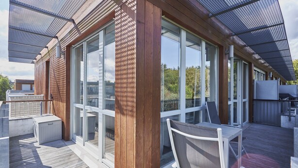 Una terraza de madera con puertas de vidrio y un porche cubierto.