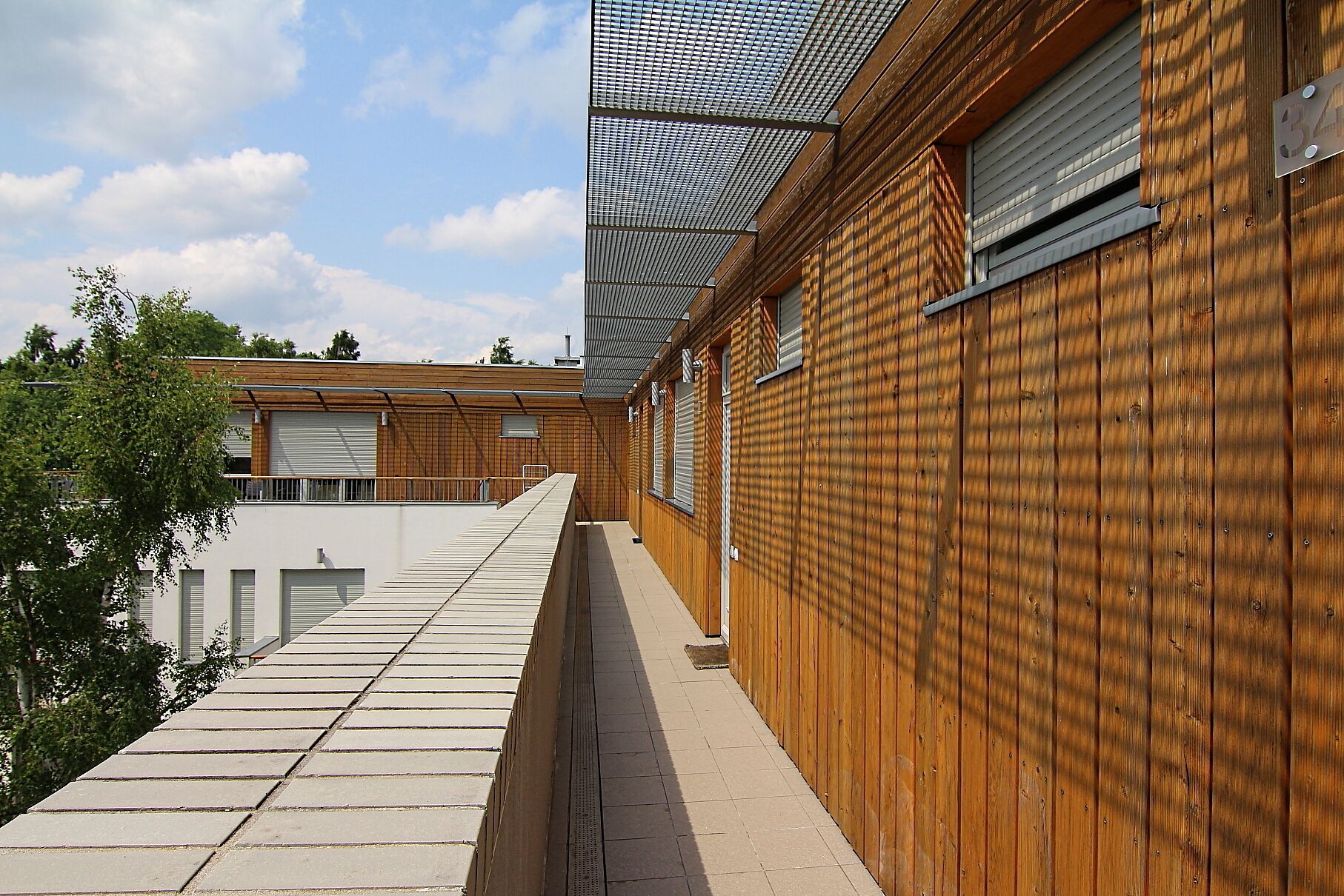 A modern building with a wooden facade, a covered walkway, and a clear sky.