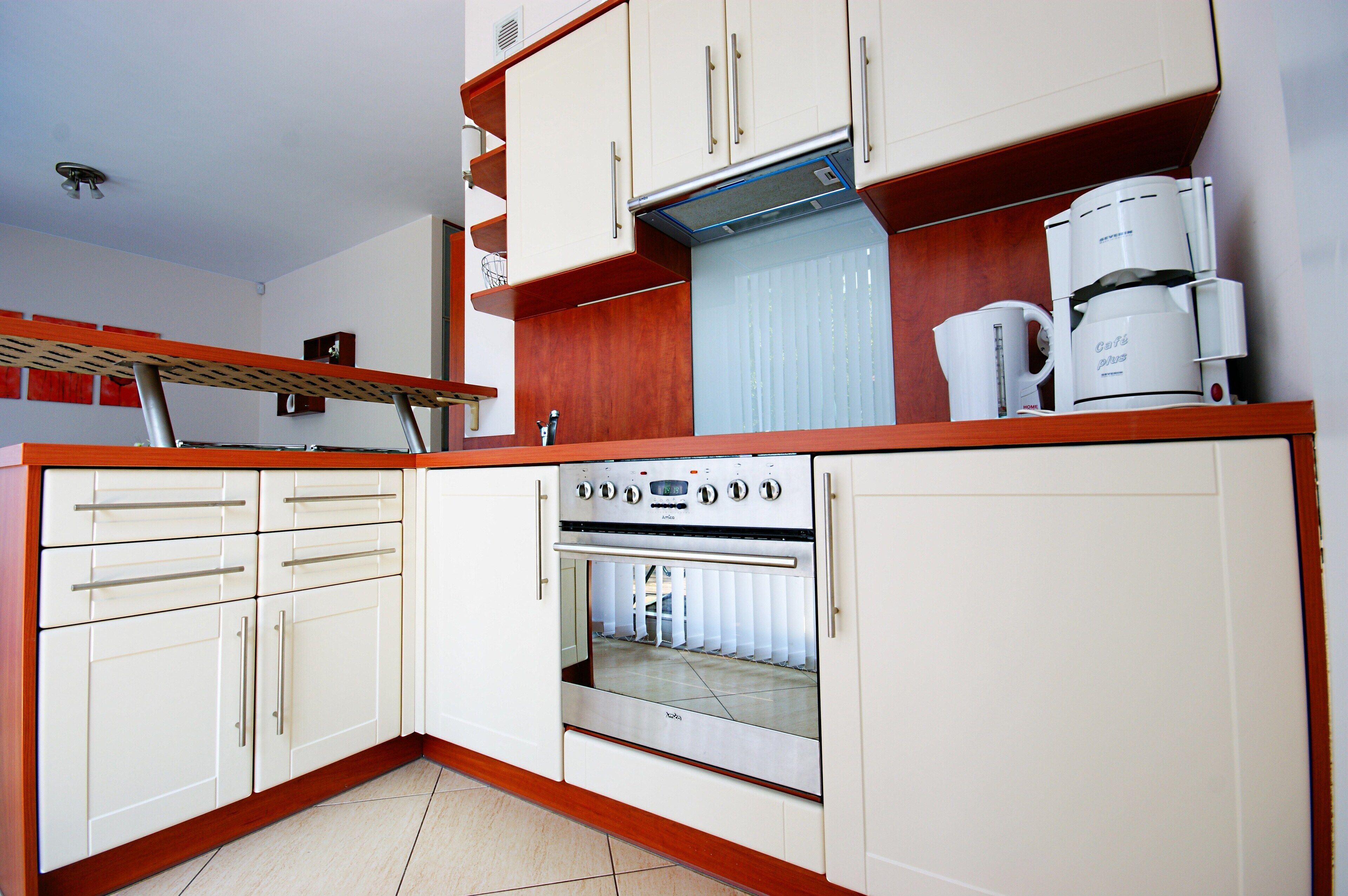 A compact kitchen with white cabinets, a built-in oven, and a coffee maker.