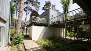 A modern house with a wooden deck, a covered outdoor area, and a staircase leading to a balcony. - Apartamenty Swinoujscie - Marinos (Swinoujscie)