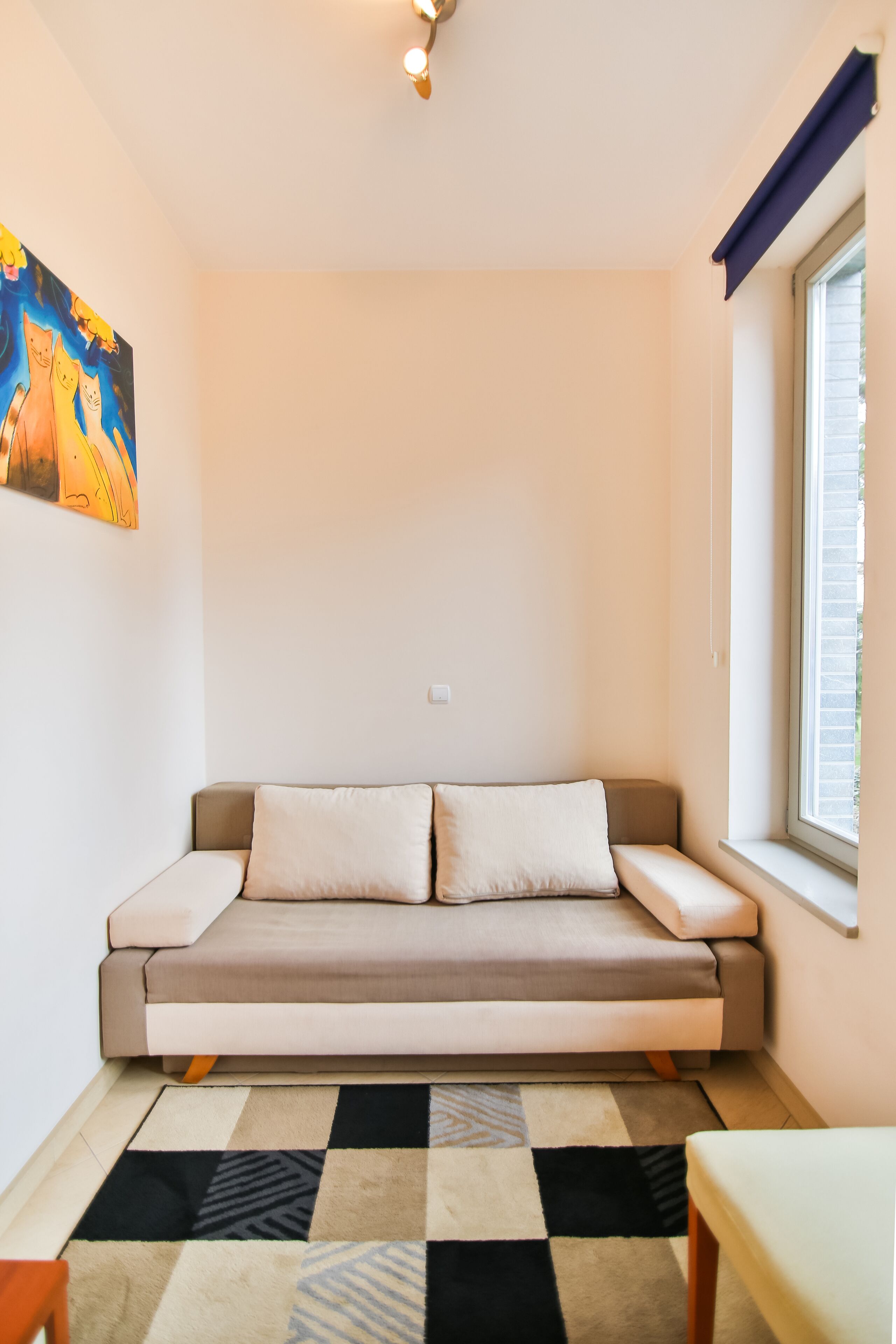 A cozy room with a sofa, a small table, and a window with blinds.