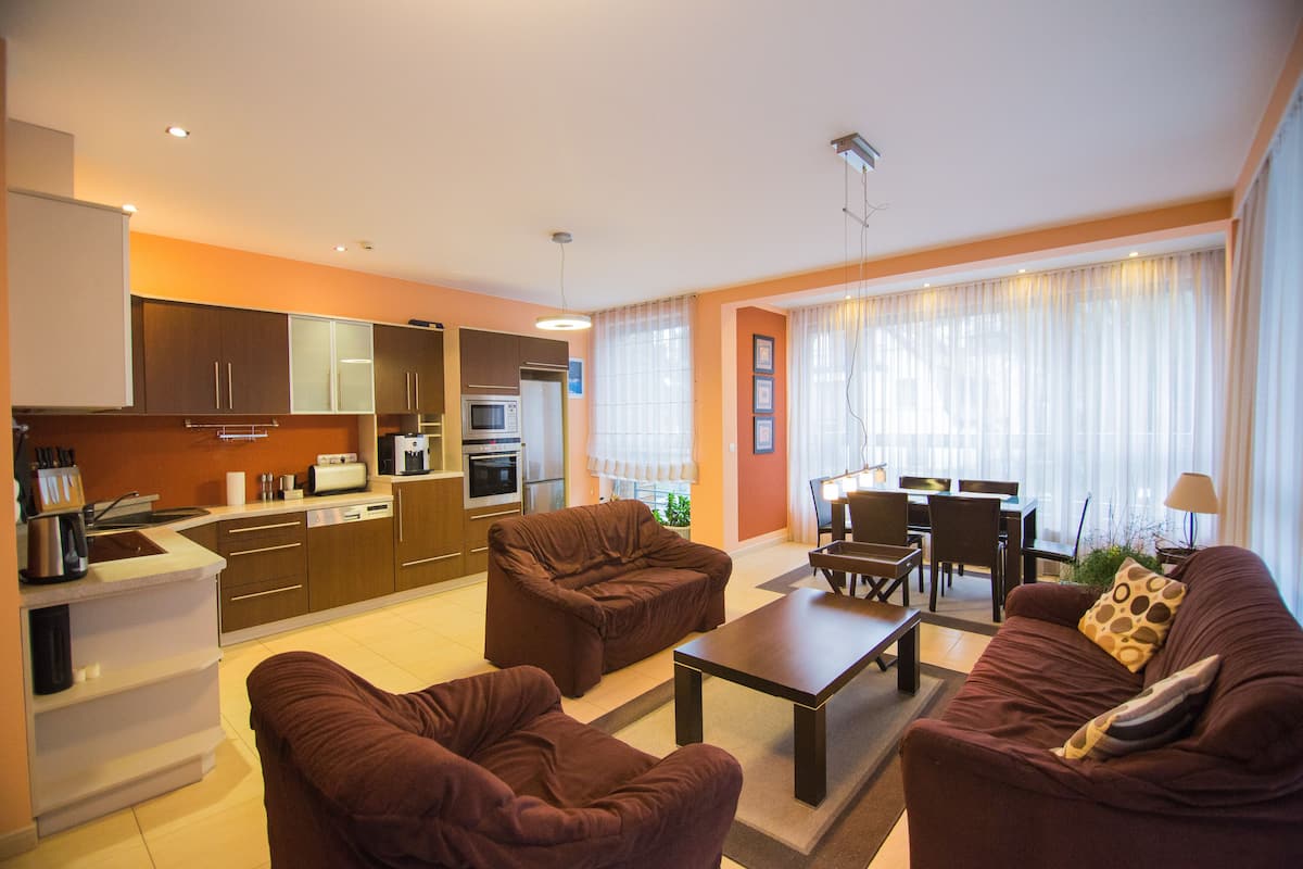 A modern living room with a sofa, coffee table, and dining area.