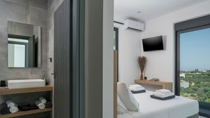 Une chambre d’hôtel moderne avec un grand lit, une salle de bain équipée d’un lavabo et d’un miroir, une télévision et une vue sur la ville.