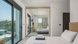 Une chambre d’hôtel moderne dotée d’un grand lit, offrant une vue sur l’extérieur et donnant sur un balcon grâce à une porte-fenêtre coulissante.