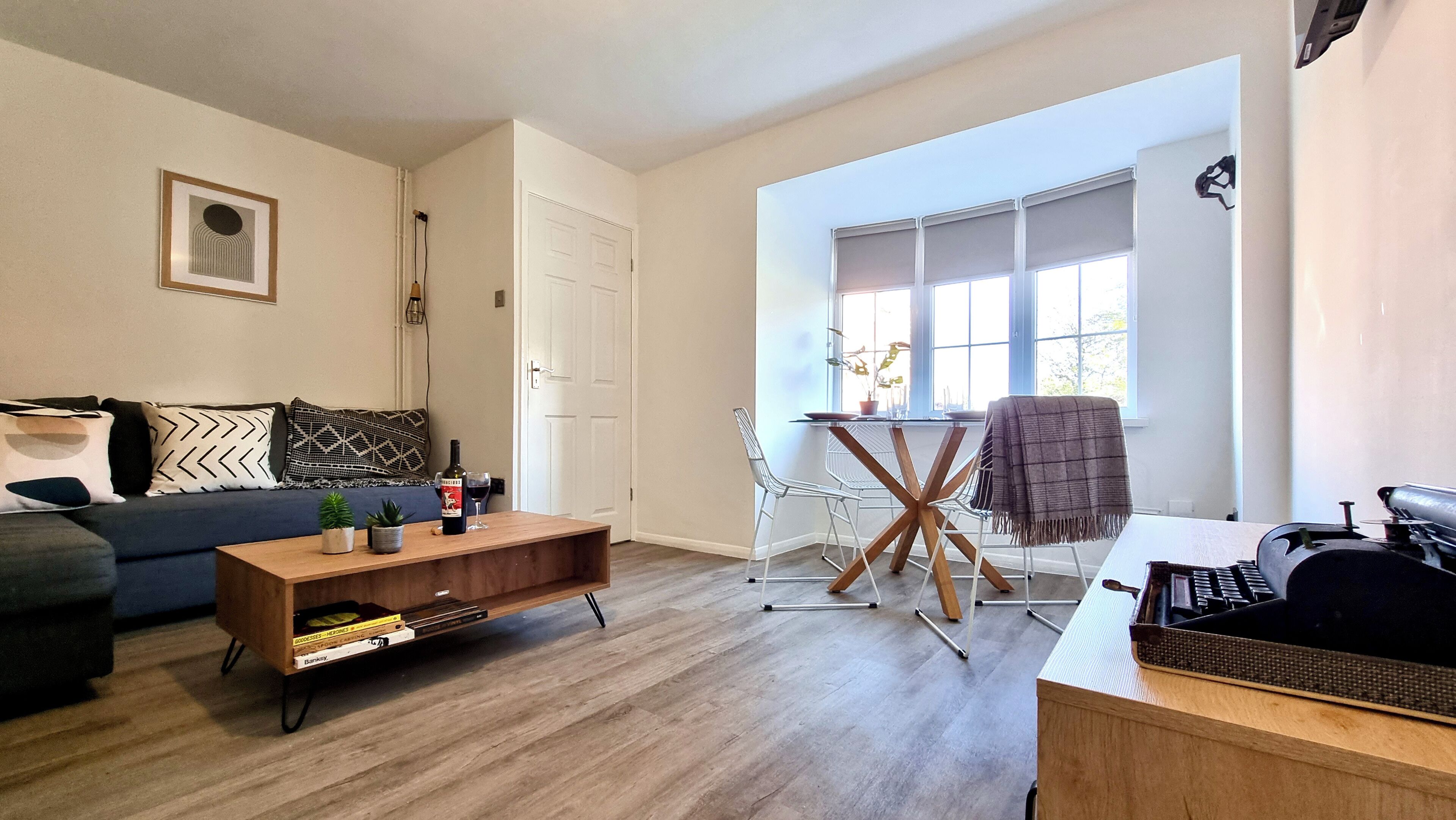 A living room with a sofa, coffee table, and a dining area with a table and chairs.