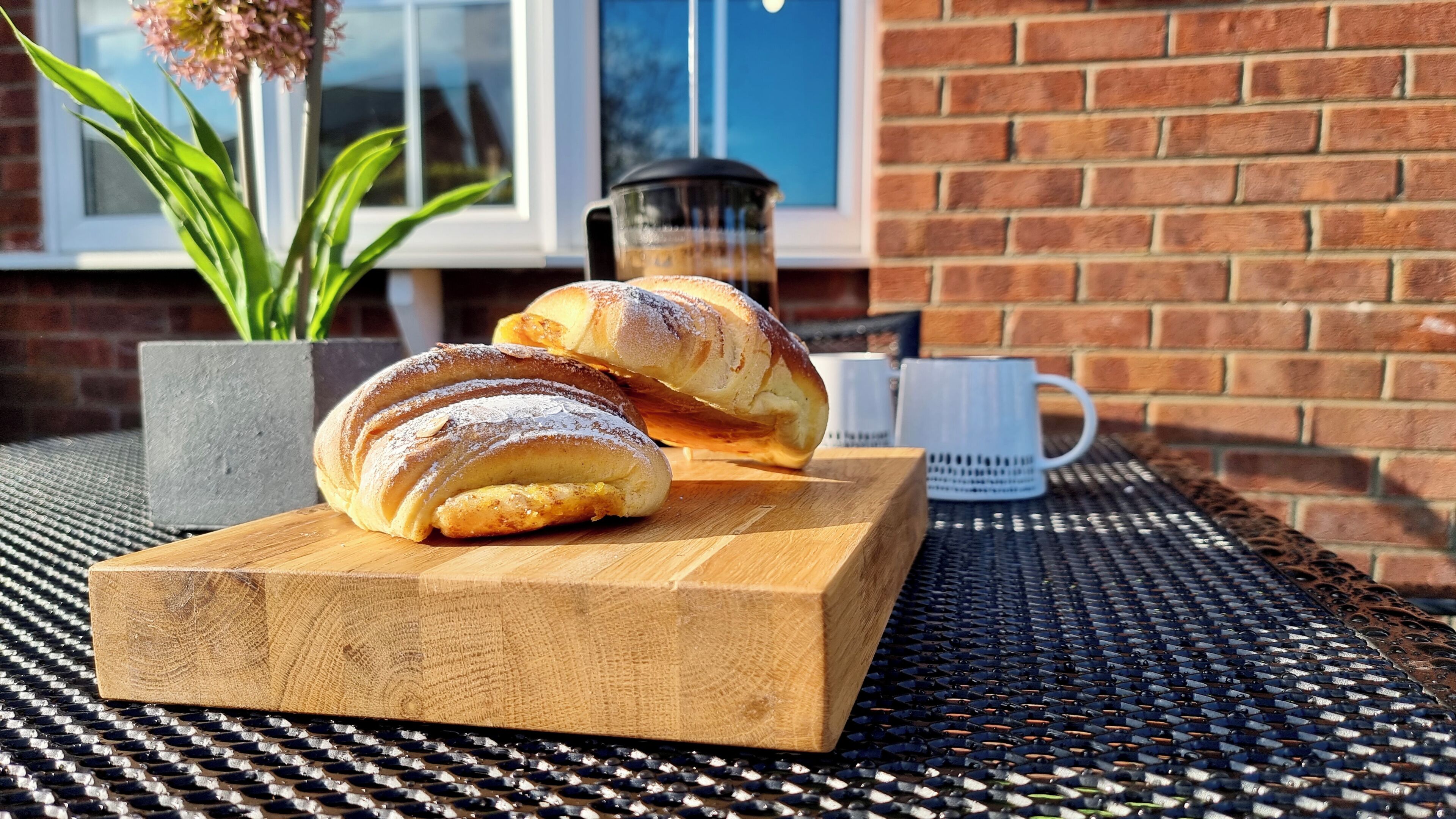 Ein Holzschnittbrett mit Brot und einer Tasse auf einem gewebten Tisch.