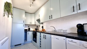 A modern kitchen with white cabinets, a black countertop, and a built-in dishwasher.
