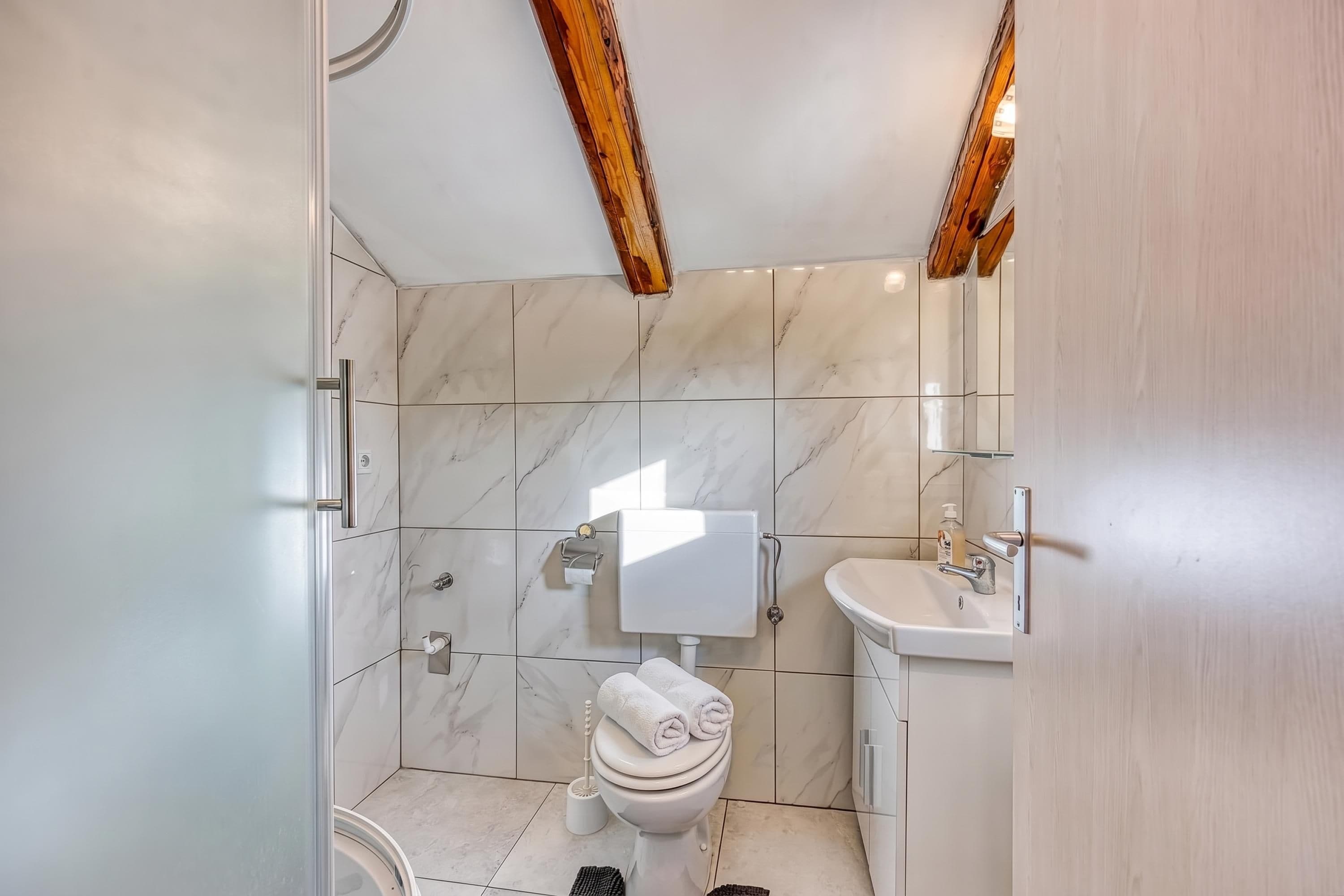 Een badkamer met toilet, wastafel en douchehoek.