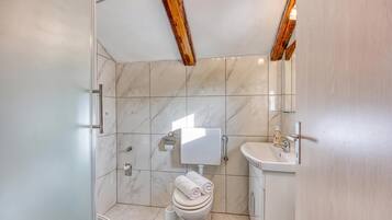 Een badkamer met toilet, wastafel en douchehoek.
