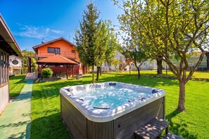 A hot tub in a backyard with a house and trees.