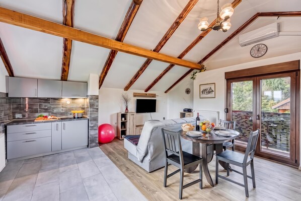 A modern kitchen with a dining area, wooden beams, and a large window.