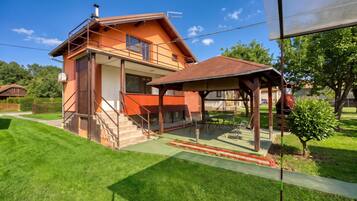 A two-story house with a covered patio and a small garden.