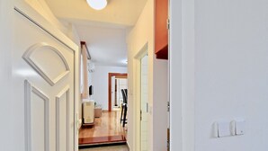 A hallway with a staircase leading to another room, a door with a light switch, and a wall-mounted thermostat. - Lovely apartment few minutes from the beach (Štinjan)