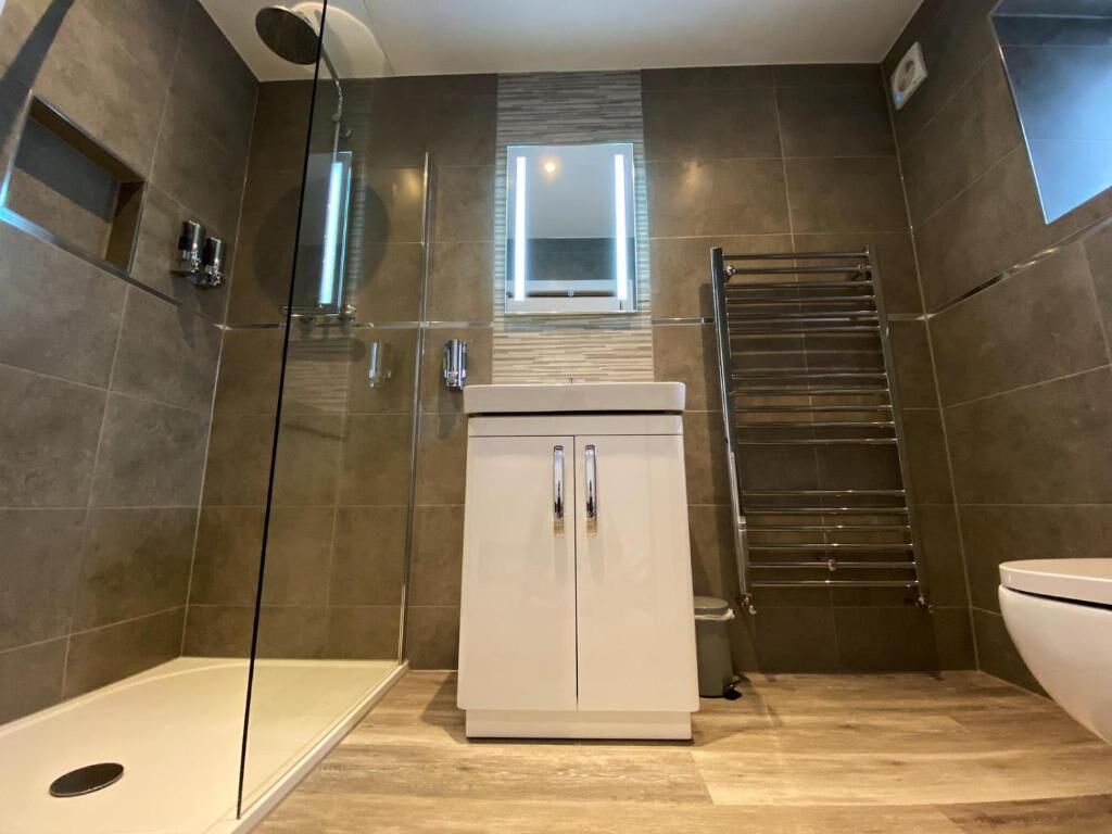 Une salle de bain moderne avec une douche à l’italienne, des toilettes et un meuble de rangement.