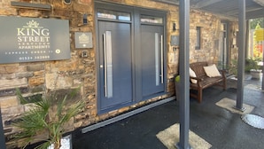 A stone facade with a blue door and a bench outside a King Street serviced apartment building. - King Street Serviced Apartments (Lancaster)