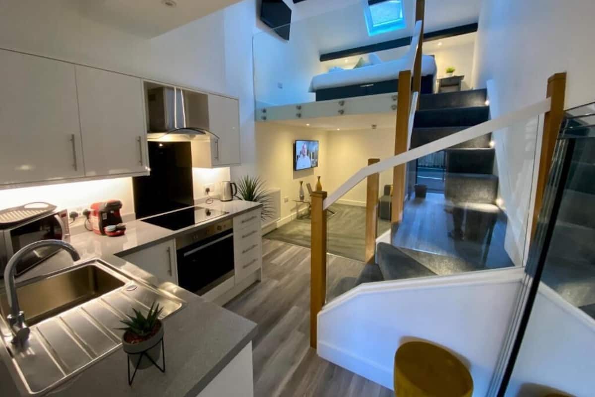 Une cuisine moderne dotée d’une cuisinière intégrée, d’un évier et d’un coin repas avec une table haute et des chaises.