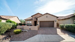 A residential house with a stone facade, a brown garage door, and a paved driveway leading to the entrance. - Beautiful Single Story Home in Gated Las Sendas Community with Private Hot Tub  (Mesa)