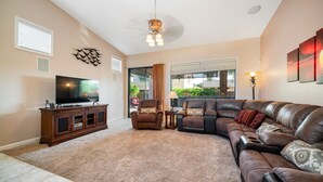 A living room with a large leather sofa, a television, and a wooden cabinet. - Beautiful Single Story Home in Gated Las Sendas Community with Private Hot Tub  (Mesa)