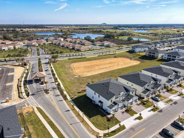 A residential area with modern houses, a parking lot, and a large open field.