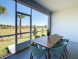 A room with a large window, a wooden table, and four chairs.
