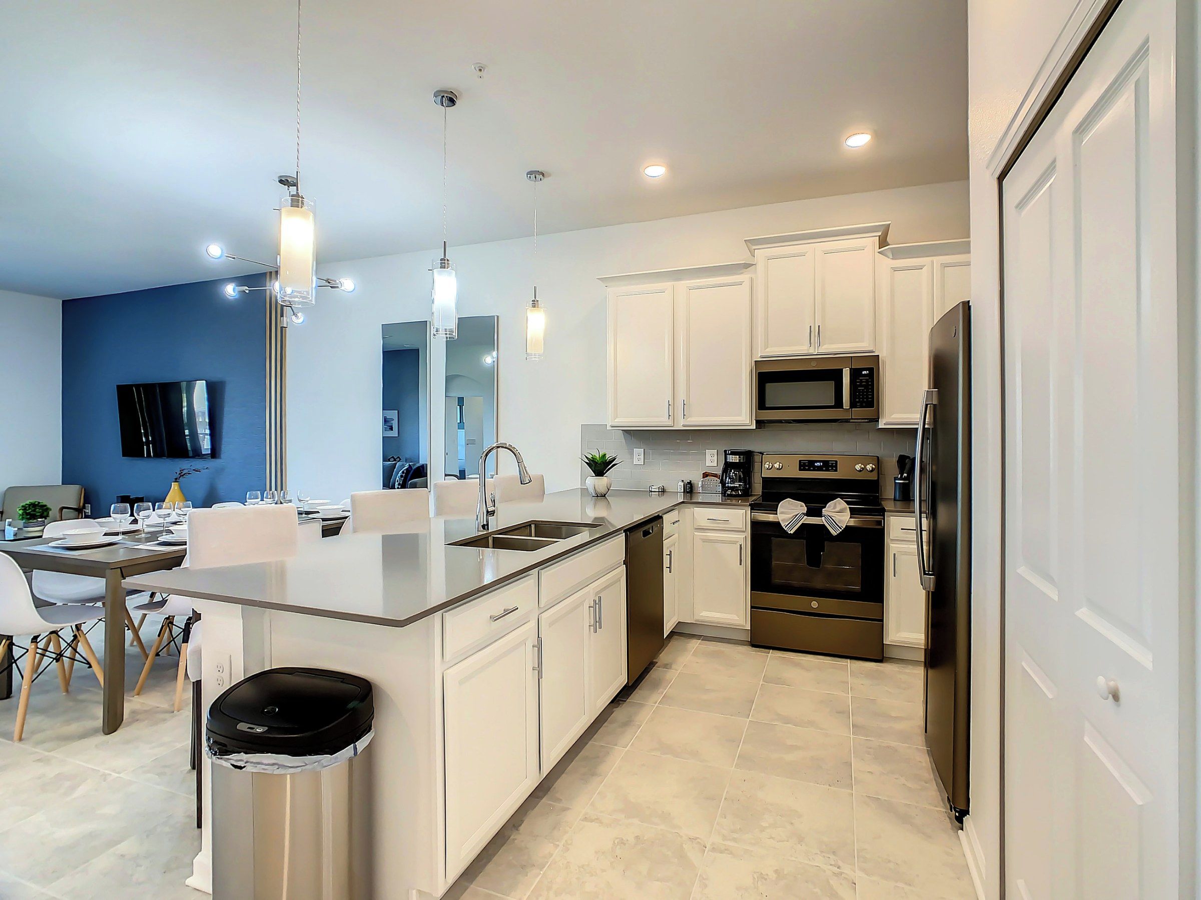 A modern kitchen with white cabinetry, stainless steel appliances, and a central island.