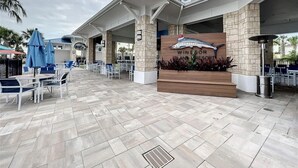 A covered outdoor seating area with tables and chairs, a sign for 'Windsor Plant Resort', and a decorative fish sculpture. - 2127LC:  10 Bedroom Home with pool, spa, and games loft! (Davenport)