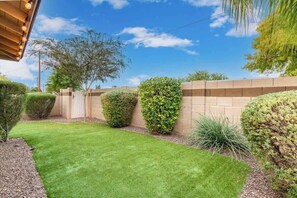 A well-maintained garden with a neatly trimmed lawn, a brick wall, and various shrubs.