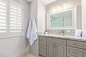 A bathroom with a large mirror, a sink, and two towels hanging on the wall.