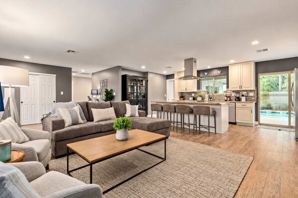 A modern living room with a sofa, coffee table, and bar stools.