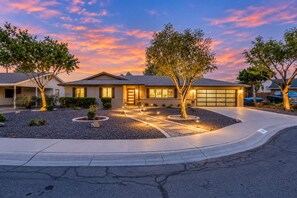 A residential house with a garage, driveway, and landscaped garden.