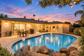 A residential property with a swimming pool, outdoor seating, and a patio area.