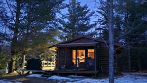 Een chalet met houten gevel, een veranda en een zichtbaar interieur met een open haard.