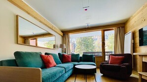 Una sala moderna con un sofá modular, una mesa de centro redonda y un sillón oscuro.
