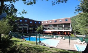 A hotel with multiple floors, outdoor swimming pool, and lounge chairs. - Charming Apartment With Swimming Pool (La Salle-les-Alpes)