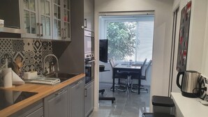 Een moderne keuken met grijze kastjes, een houten aanrecht en een zithoek met een tafel en stoelen.