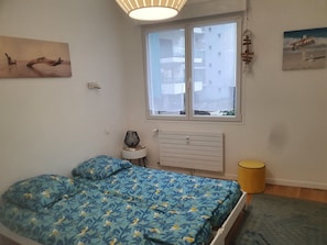 Une chambre à coucher avec un lit, une fenêtre, un radiateur et une lampe.