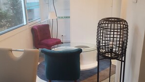 Een moderne woonkamer met een rode stoel, een blauwgroene fauteuil en een zwarte stoel met een draadframe.