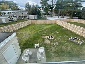 A backyard with a fire pit, a table, and chairs.