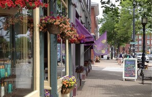 A street with storefronts, including a hair salon and a natural foods shop.