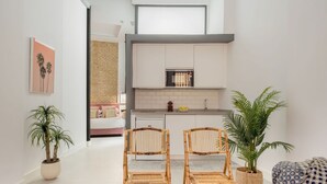 A modern living room with two wicker chairs, a sofa, and a large potted plant.