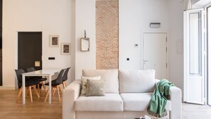 Een moderne woonkamer met een witte bank, een eettafel met stoelen, een laptop en een ontbijttray.