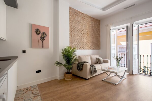 Un salon moderne avec un canapé, une table basse, une plante en pot et un mur en briques.