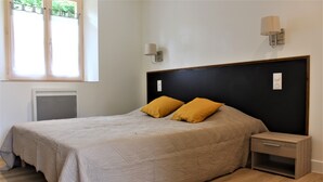 Una camera da letto con un letto, due lampade da comodino, un comodino e una finestra con persiane.