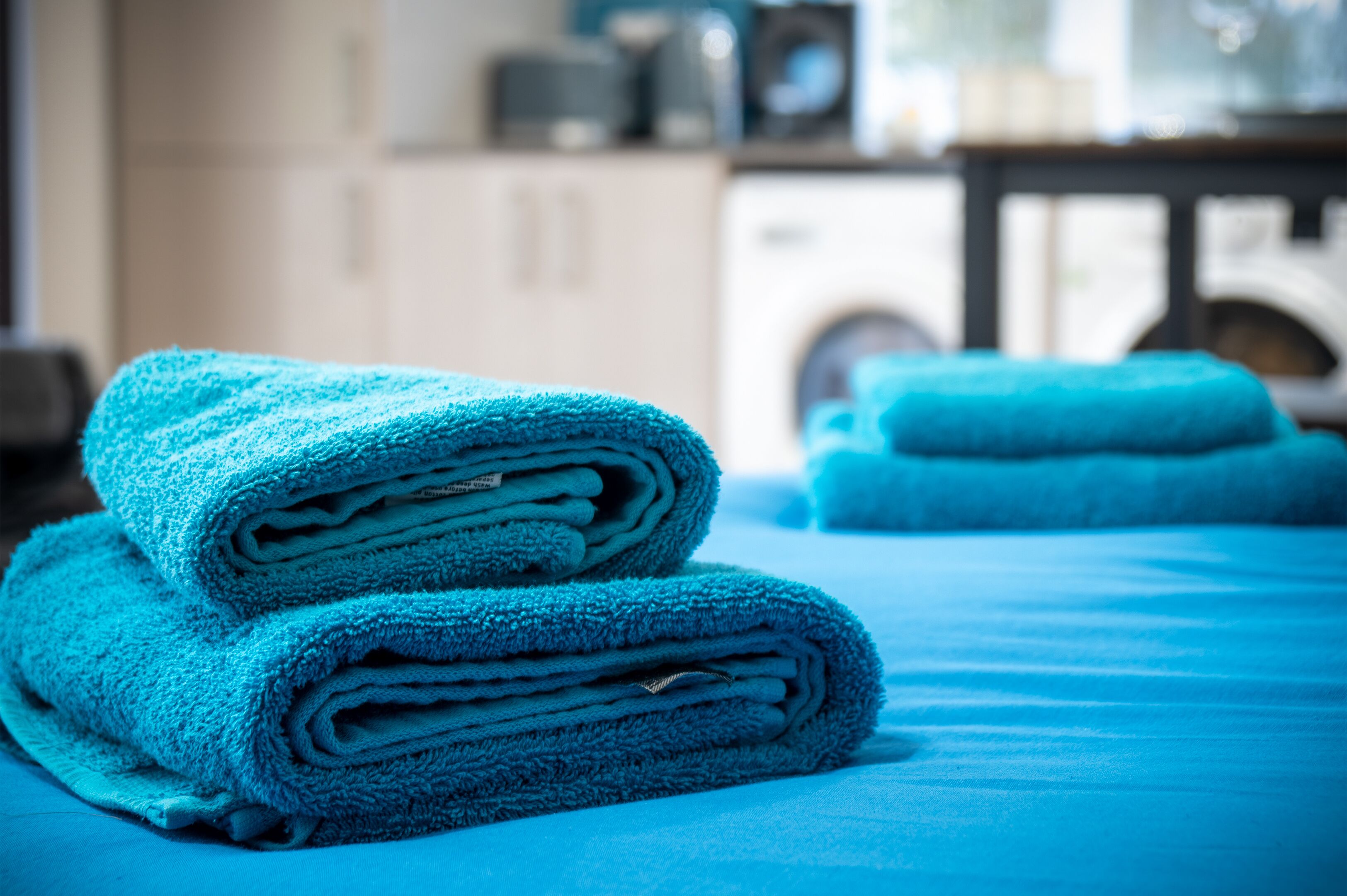 Una toalla azul doblada con cuidado sobre una cama en una habitación de hotel.