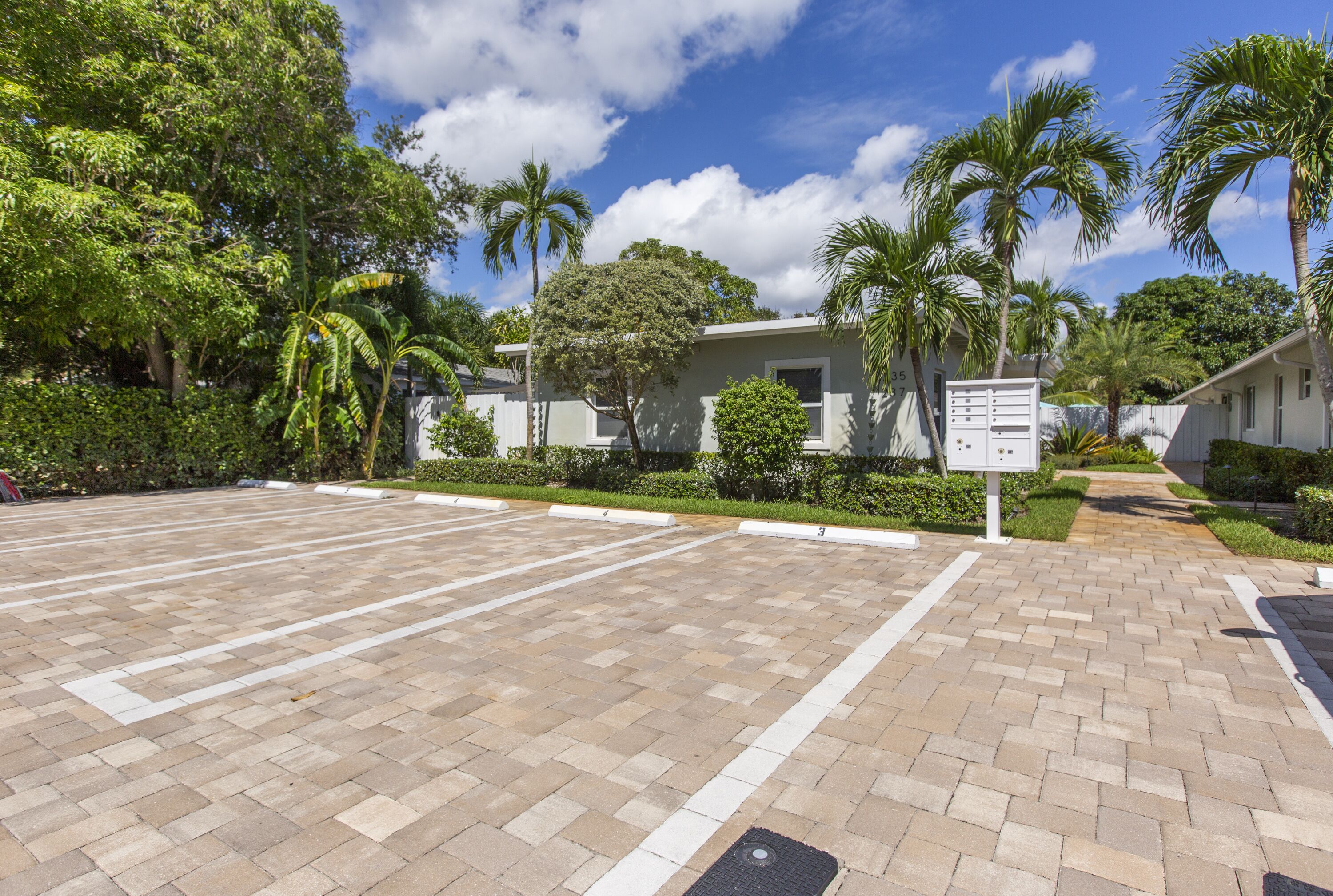A parking lot with a paved walkway leading to a building with a white exterior and a signboard.