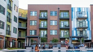 A multi-story residential building with a swimming pool, outdoor seating, and balconies. - Downtown Indy Apartment w/ Balcony, Pool & Parking (Indianapolis)