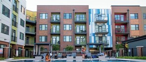 A multi-story residential building with a swimming pool, outdoor seating, and balconies.