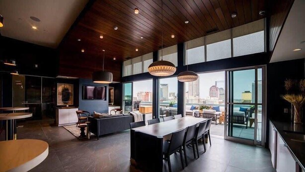 A modern interior with a dining area, kitchen, and large windows offering a city view. - Downtown Indy Apartment w/ Balcony, Pool & Parking (Indianapolis)