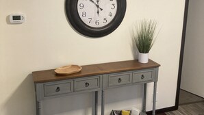 Une horloge murale, une petite plante en pot et une console grise dotée de tiroirs et d’étagères.