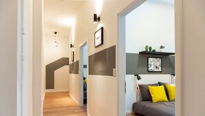 Un intérieur moderne avec un plancher en bois, un canapé agrémenté de coussins jaunes et une étagère murale ornée de plantes.